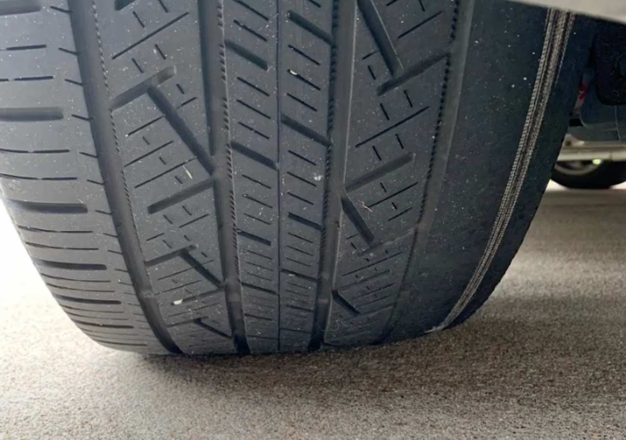 Real tire showing a worn inner tread shoulder on the right of this photo, beside deeper remaining tread